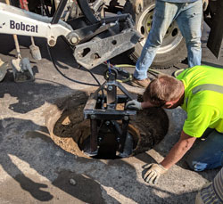 Worker using the manhole ring lifter