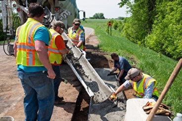 Maintenance workers pouring concrete on a roadside