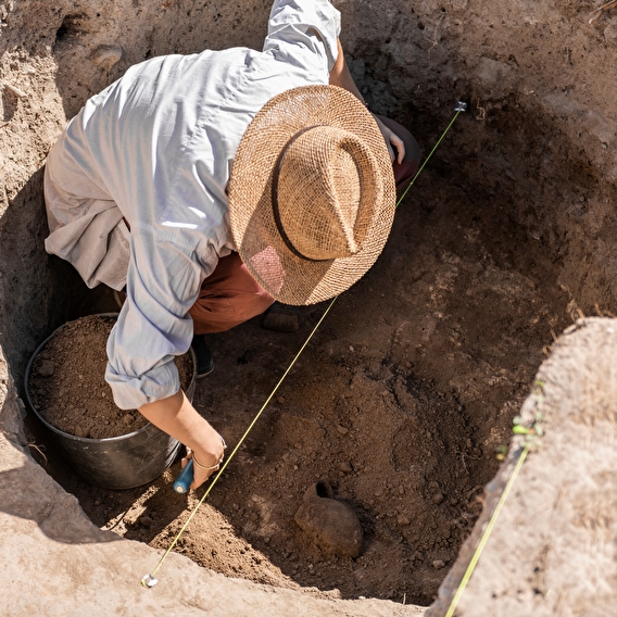 Man digging in dirt hole looking for remains