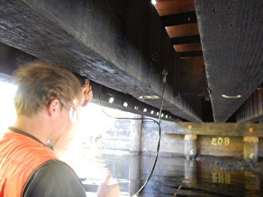 Person inspecting the underside of a bridge